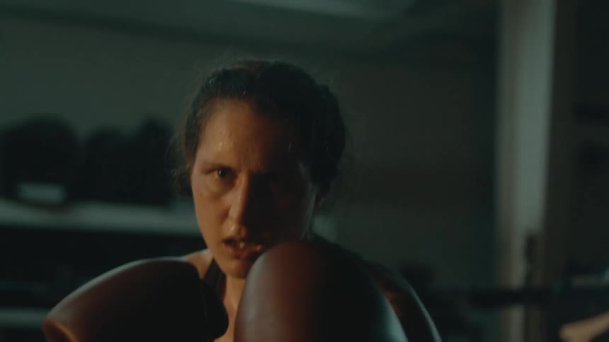 A woman looks angry as she boxes with gloves on