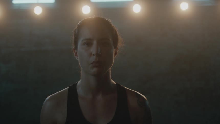 A female athlete stares into the camera as she comes to stand before it