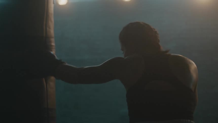 A female boxer hits a punching bag in a gym