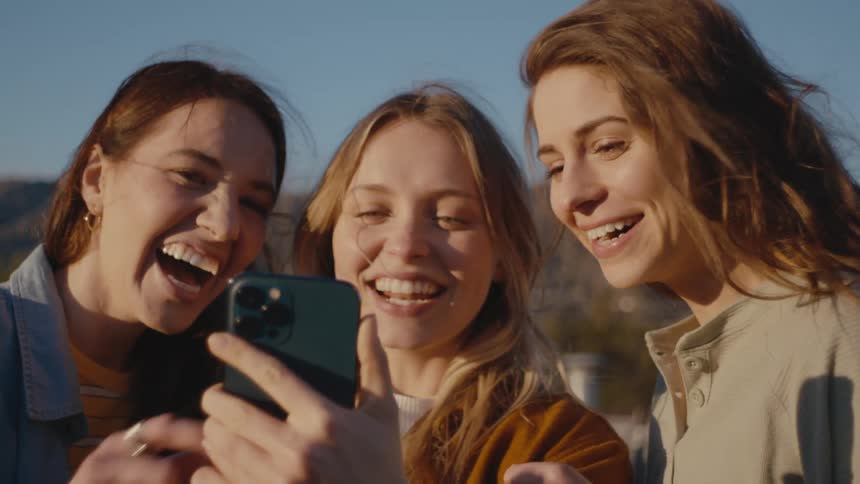 Three women look at a cell phone together