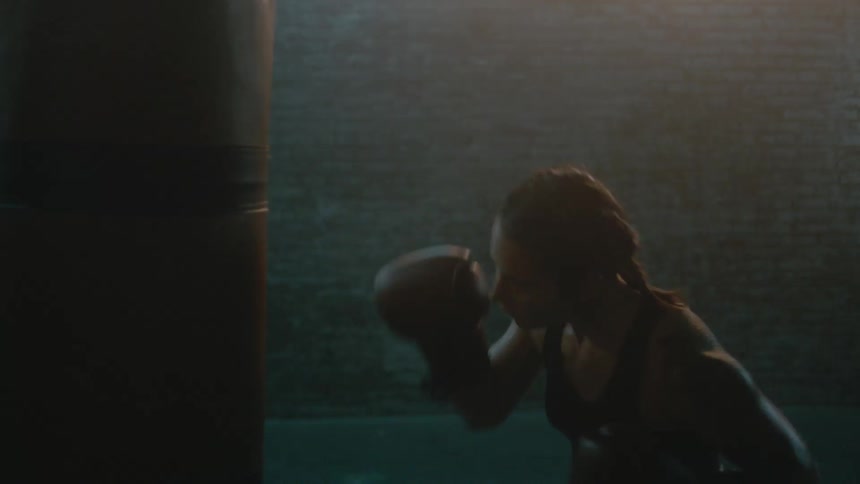A woman throws punches at a bag as she boxes