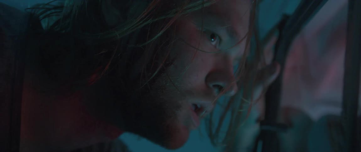 Close up of the bloodied face of a fearful blonde long haired man looking out a window