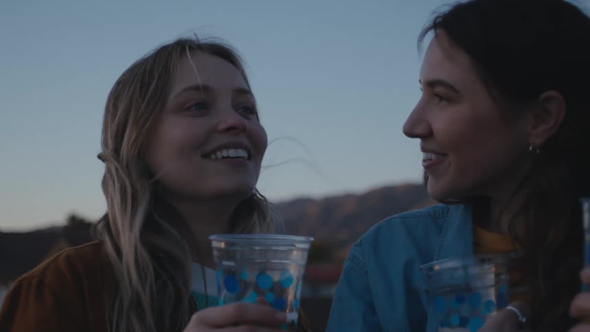 Two friends are outdoors and drinking together on a rooftop