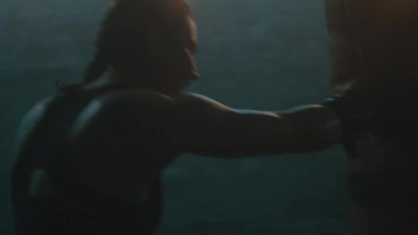 A woman punches a punching bag with her boxing gloves