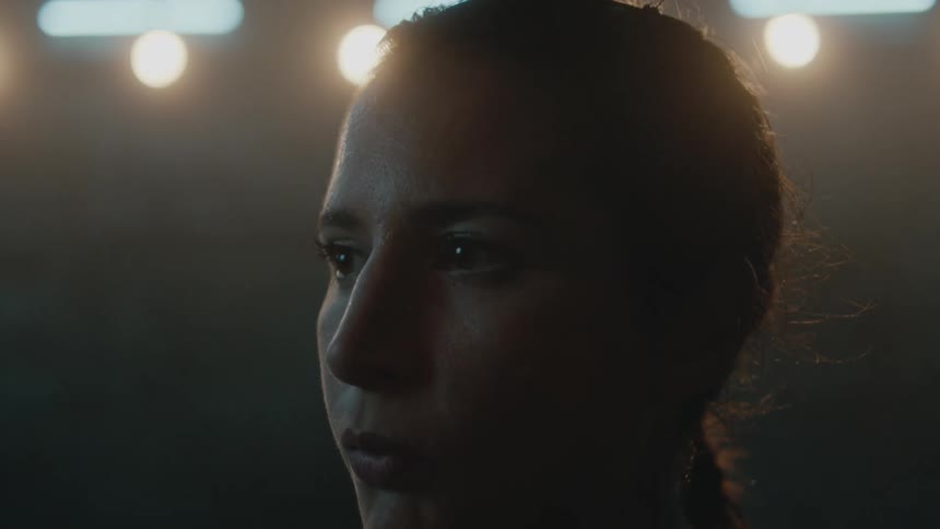 Female boxer with braids looks to the side in gym
