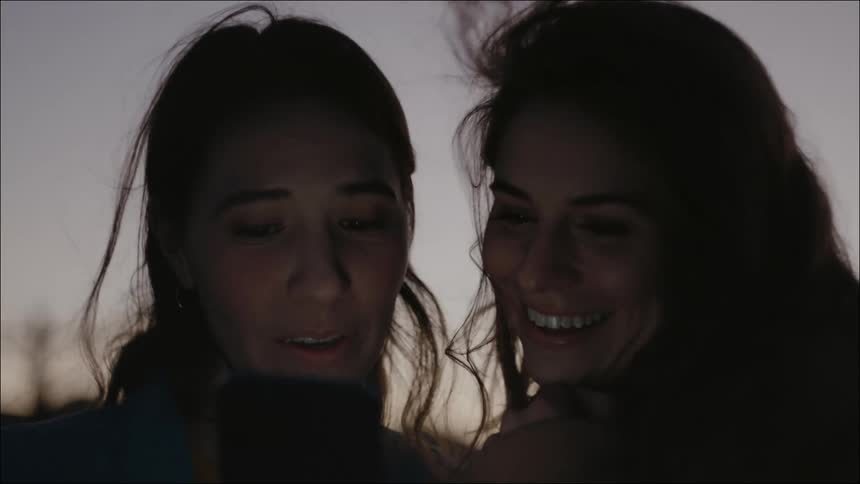 Two women talk and look at a phone