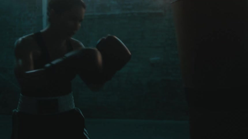 A woman wearing boxing gloves is hitting a punching bag in a gym