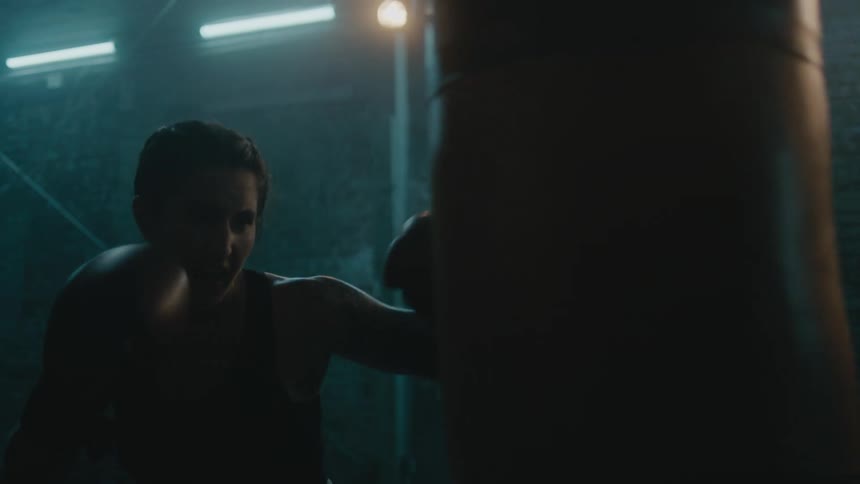A woman is punching a boxing bag indoors