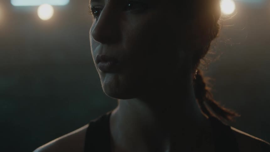 Female boxer with braids and sports bra stands in boxing ring