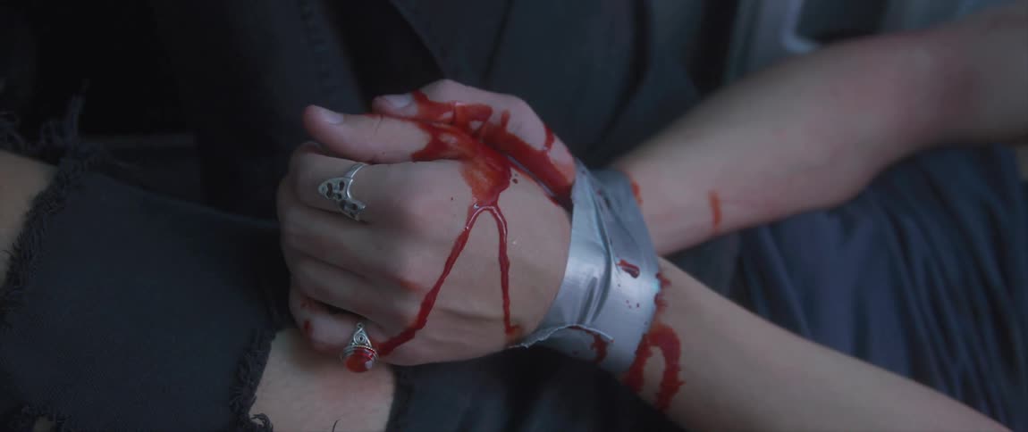 The hands of a woman are covered in blood as silver duct tape binds her wrists