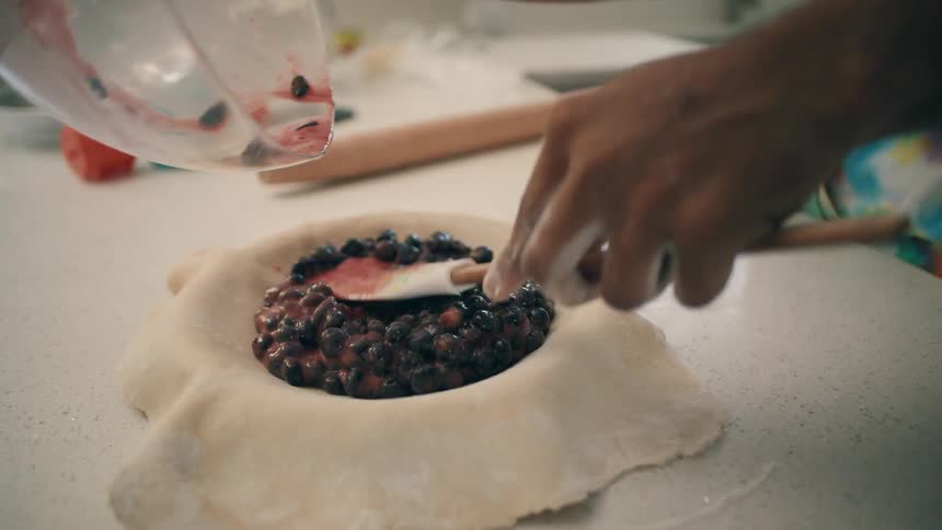 Blueberries poured and spread into a pie crust for baking