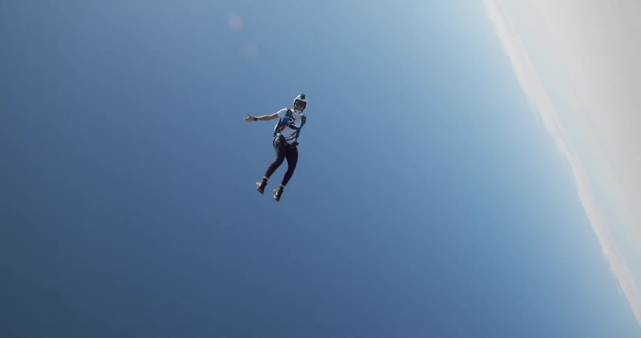 Free falling skydiver wearing a helmet parachuting from an airplane over land