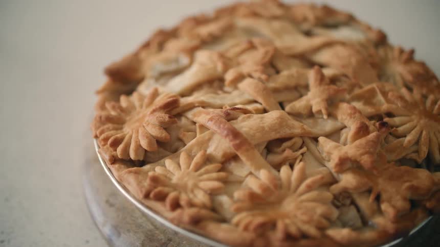 A pie with a decorated crust sits on a counter