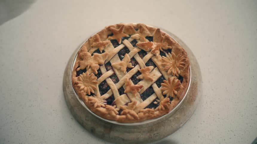 A person sets a cooked pie on the kitchen counter