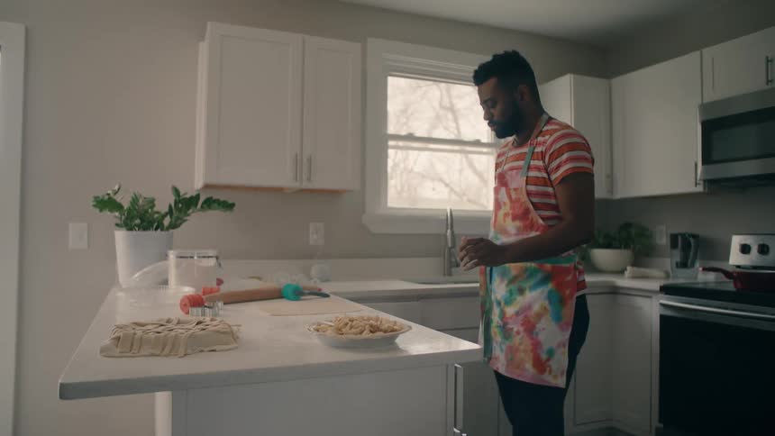 Man wearing an apron doing a little dance while baking pies in the kitchen