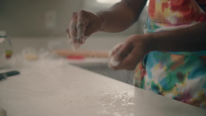 Man sprinkling flour on kitchen counter to prepare for baking