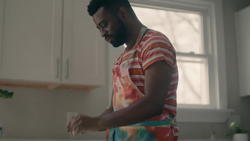A man is preparing a meal in his kitchen during the day