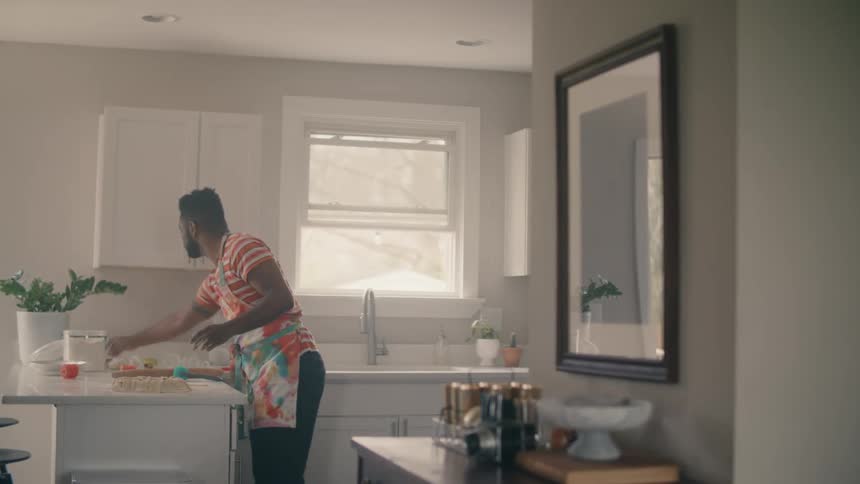 A man wearing an apron is cutting dough on a kitchen counter
