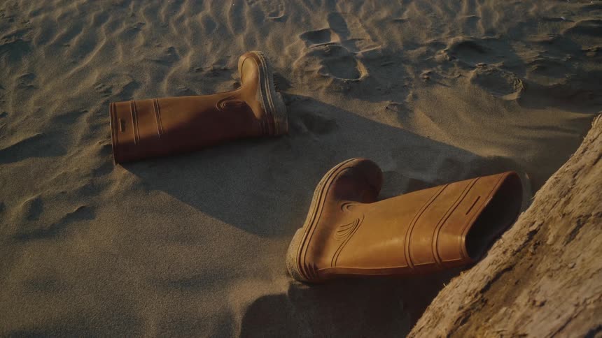 A pair of boots are left on the sandy coast