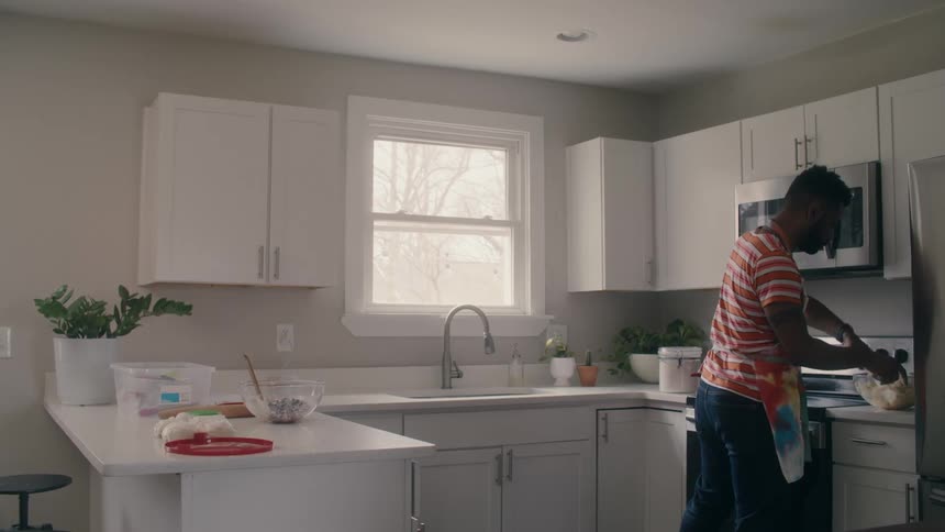 A man is cooking a meal in his kitchen during the daytime