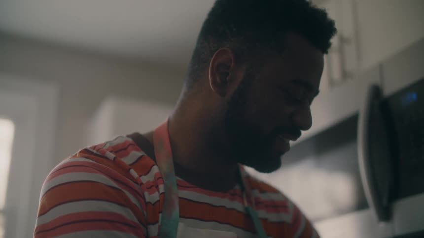 Man in apron smiles as he moves in the kitchen