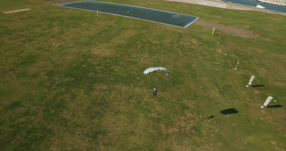 Aerial view of a skydiver parachuting over a field near the coast at daytime