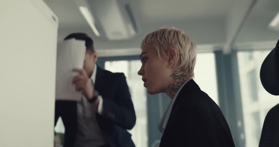A man yells at an employee shaking his head slams papers down then gets up to talk to the rest of the office