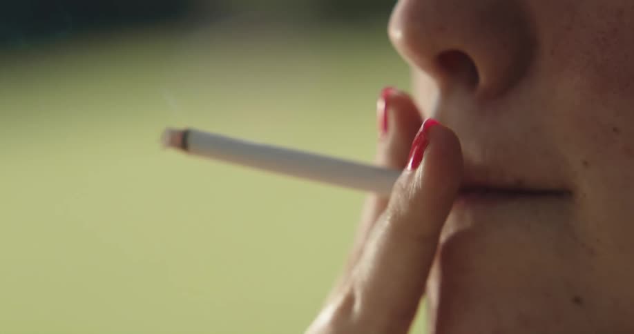 Close up view of a woman smoking a cigarette outdoors