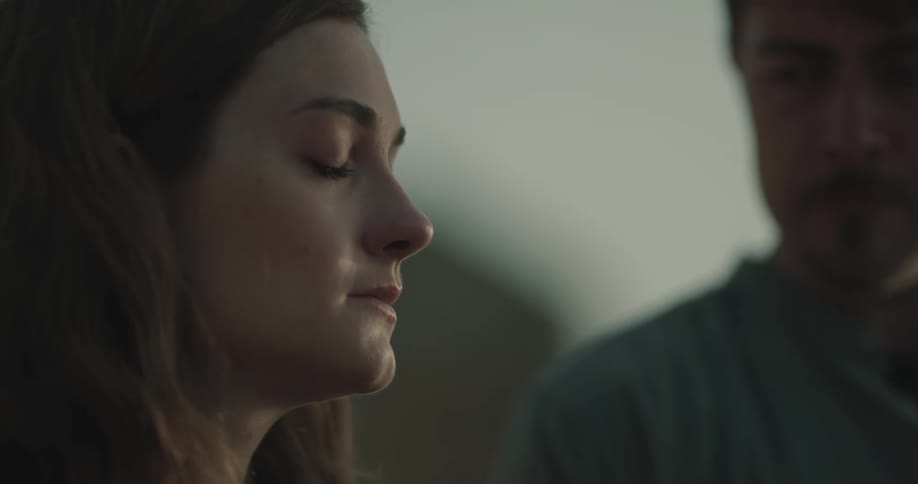Woman and man stand outdoors and exchange sad looks