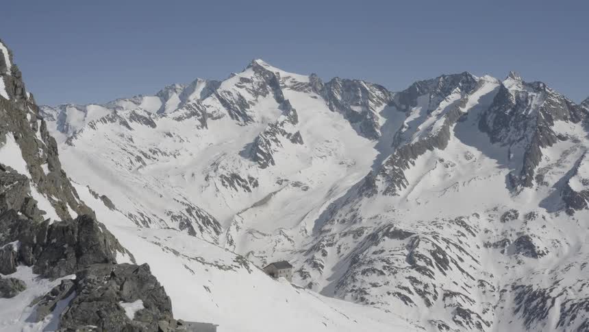 A rocky mountain range that is partially covered in snow on a sunny day