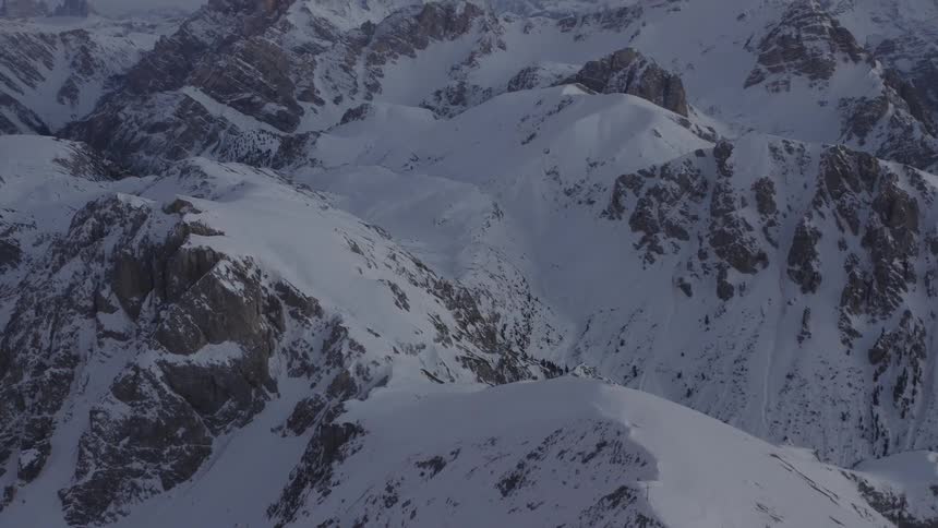 A rocky mountain range partially covered in snow at sunrise