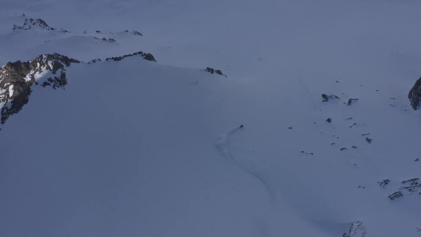 Aerial view of a person skiing down the snow covered slopes of a mountain in winter