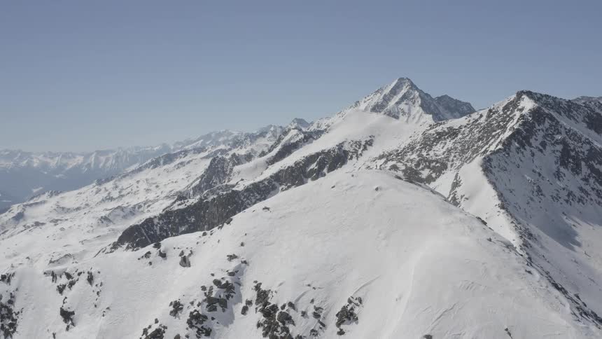 Snow covered mountains with peaks high in a clear blue sky
