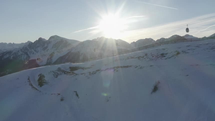 Aerial view of cable cars moving over a ski piste in the mountains at evening
