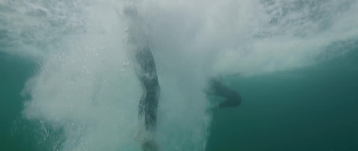 Underwater footage of a swimmer wearing a black wet suit plunging into the ocean
