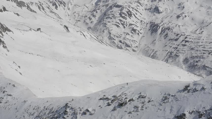 A skier glides down the slope of a steep mountain