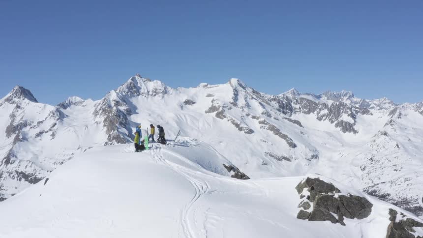 A group of people are standing on the summit of a snow covered mountain