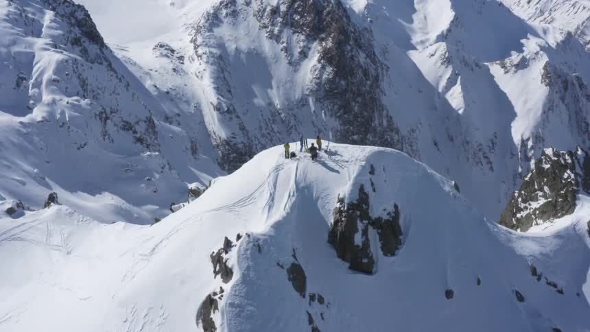 A group of mountaineers stand together atop a snow covered mountain during the day