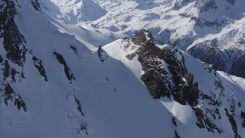 A pair of skiers descend a steep mountain slope