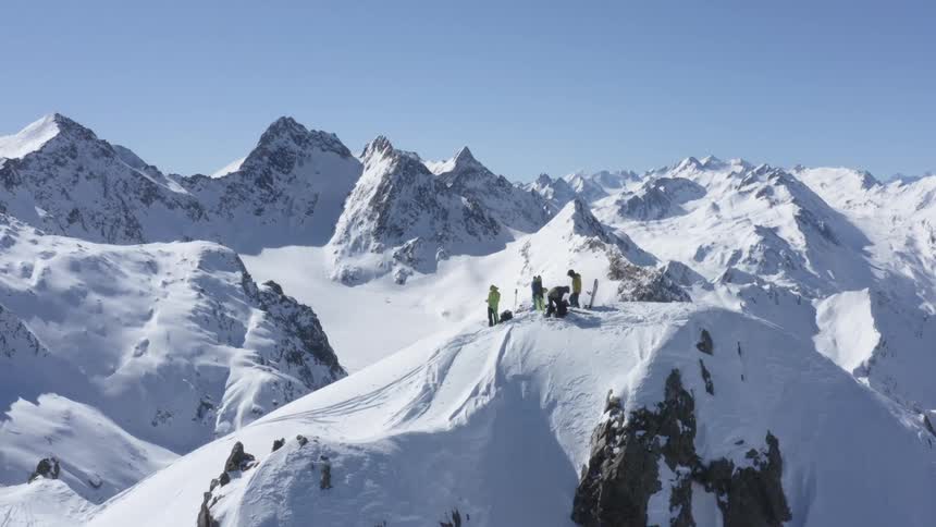 Aerial view of a group of skateboarders standing atop a snow covered mountain