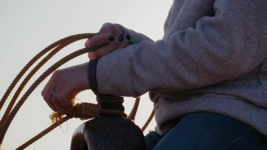 A person is sitting in a saddle and holding reins