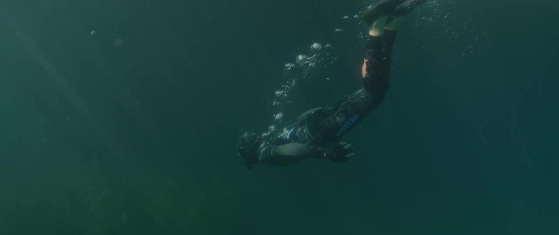 Underwater footage of a diver submerging under the surface of the ocean