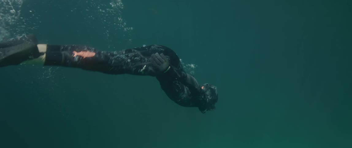 A person takes a deep breath to free dive in a lake