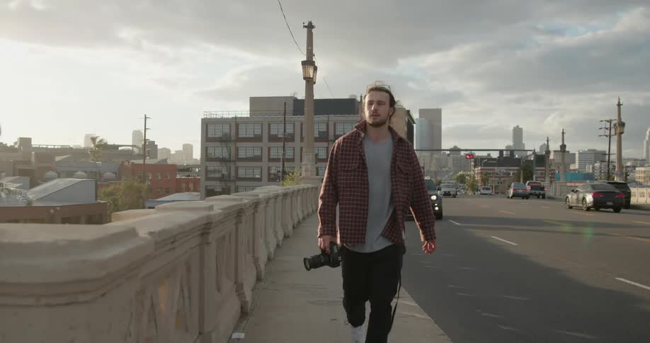 A photographer walks across a traffic bridge in a metropolis during the day