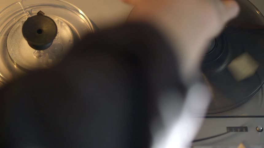 A man is winding tape onto a machine and it starts spinning