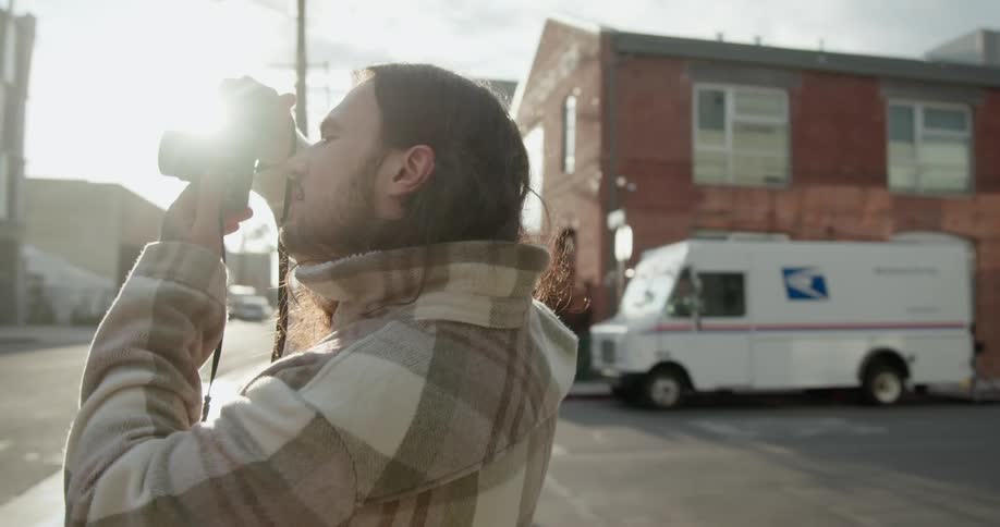 Young long haired man takes pictures of the buildings on the street of a small town