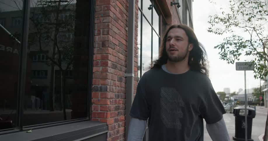 Photographer carries camera while walking down street past closed sidewalk sign