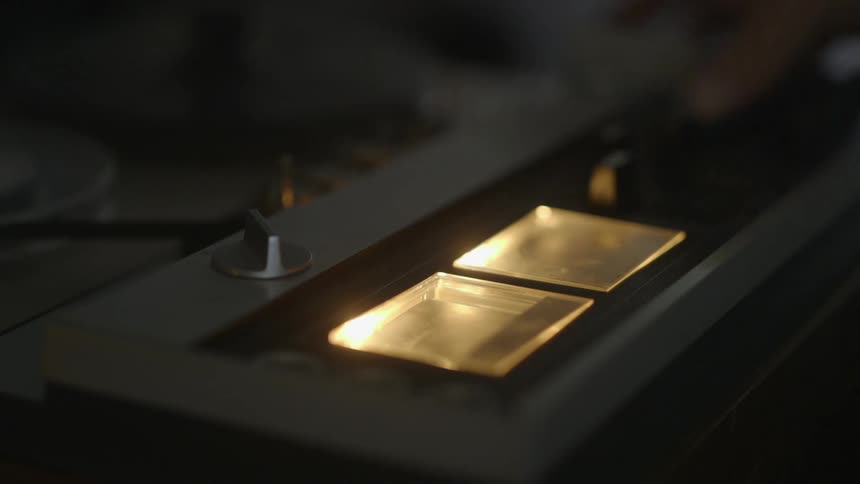 A person adjusts dials on a machine and tape starts moving