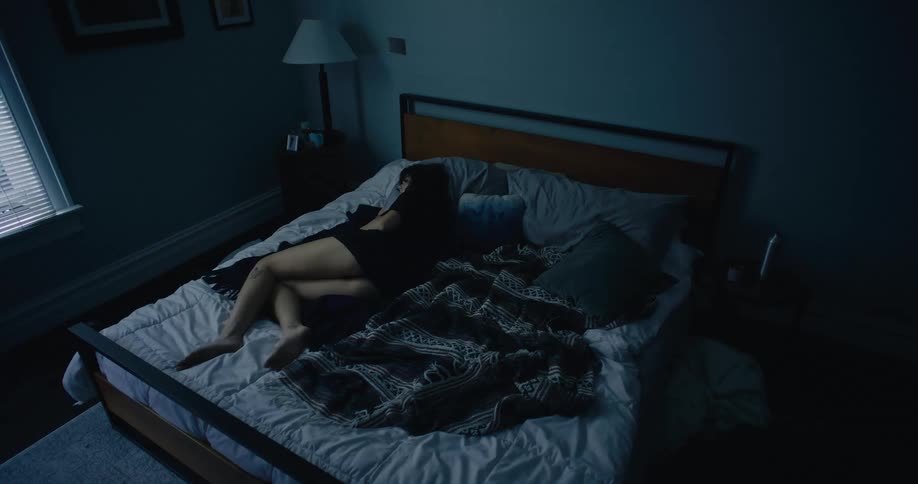 A woman is laying in bed in the morning and starts to turn over