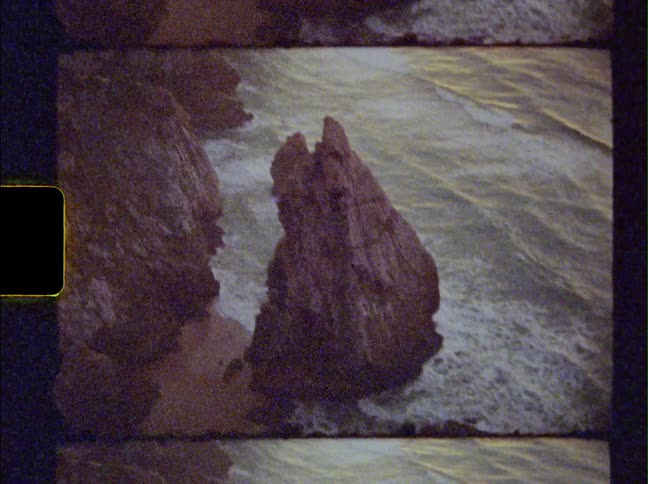 The waves crash against the rocks on the shore